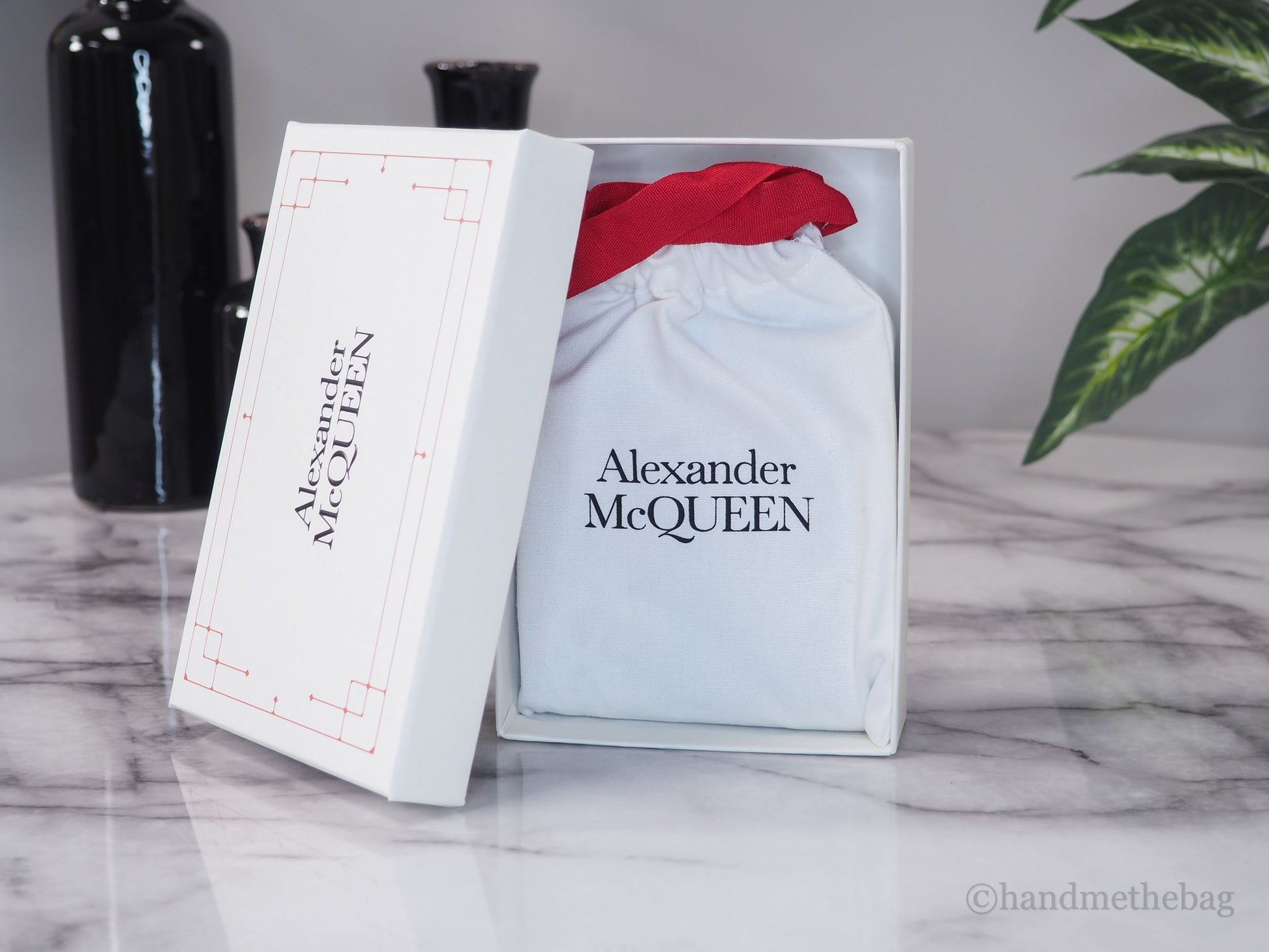 Alexander McQueen wallet dust bag and box on marble table