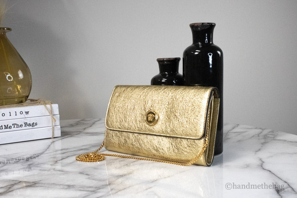 versace metallic gold evening bag on marble table
