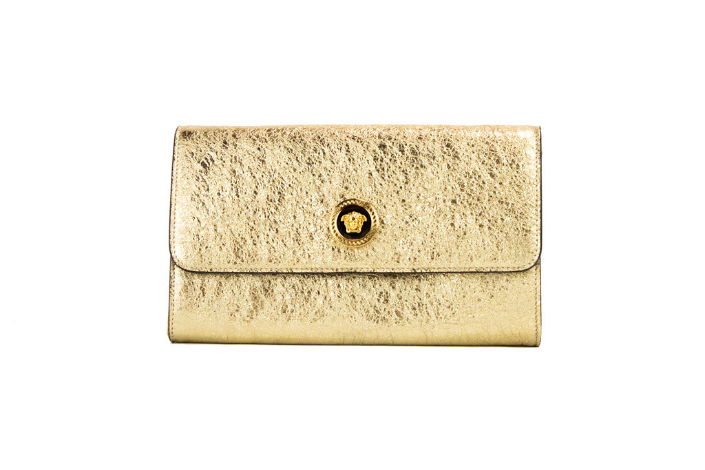 versace metallic gold evening bag on white background